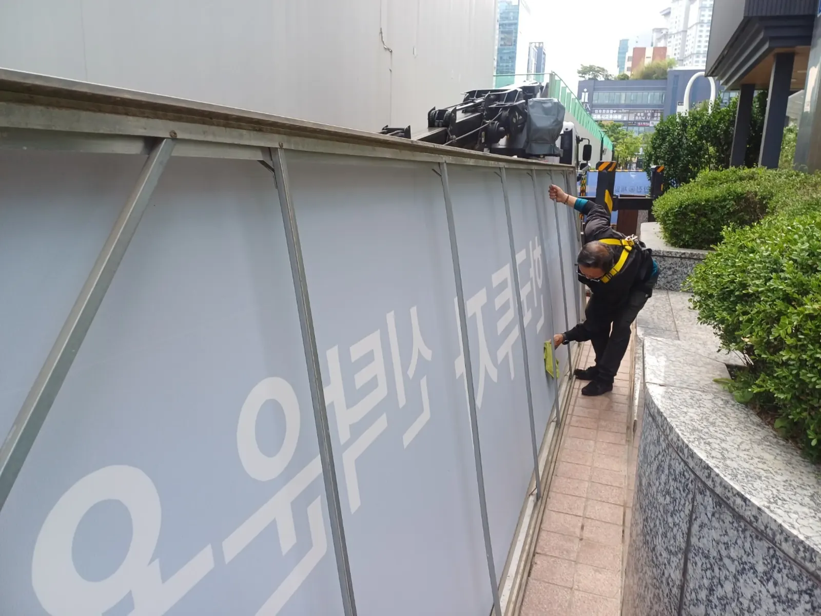 증권사 외부 LED 전광판 시간 표시부를 고소작업대에서 점검하는 작업자