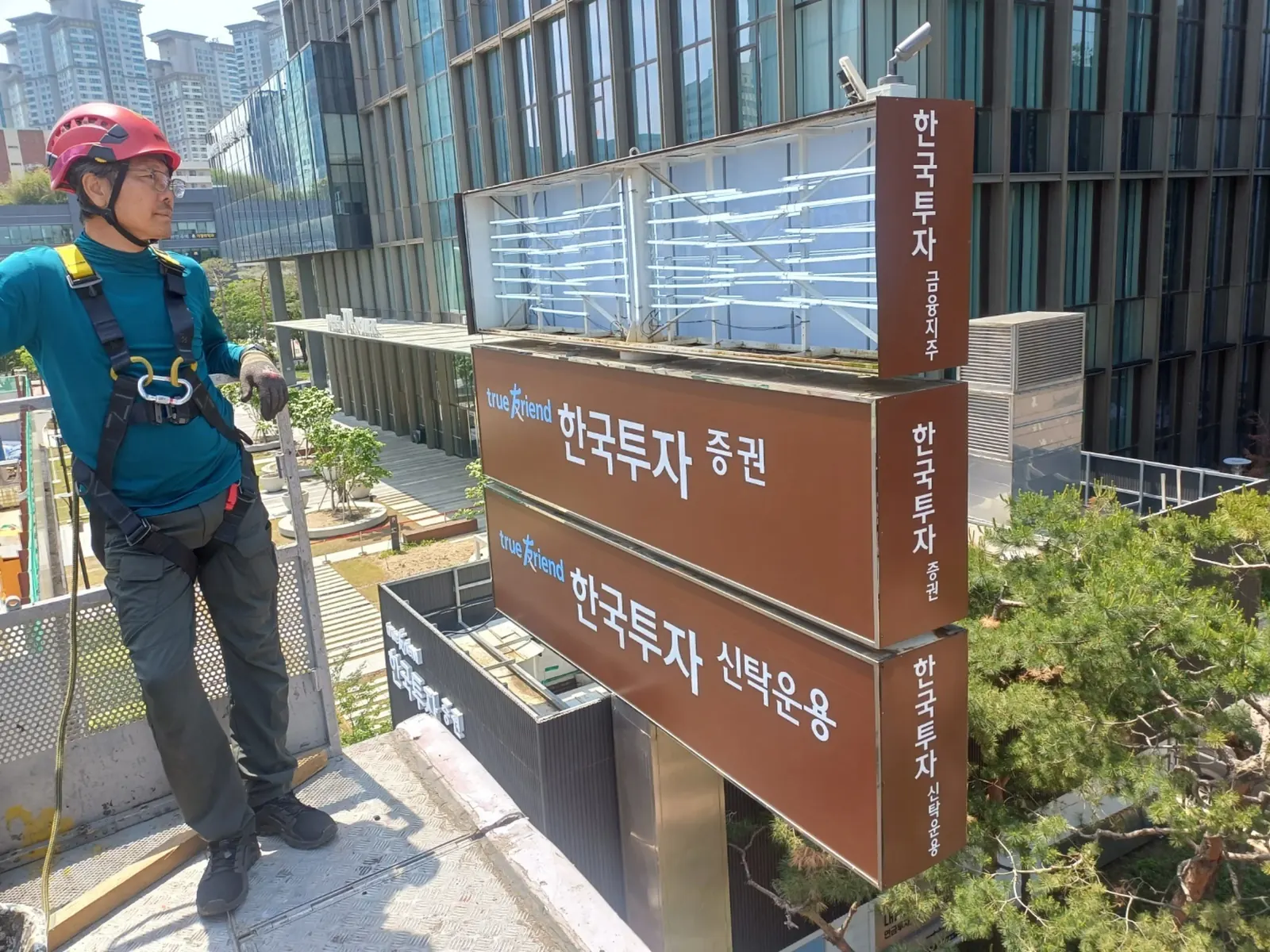 옥상 모서리에 설치된 외부간판을 근접 점검하는 작업자